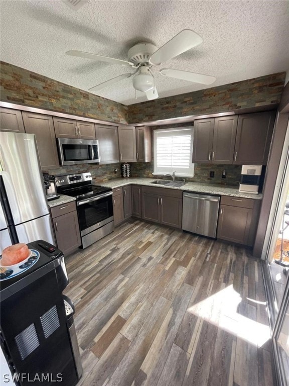 kitchen featuring appliances with stainless steel finishes, wood-type flooring, ceiling fan, and dark brown cabinets