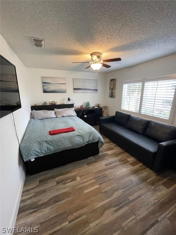 bedroom with ceiling fan, a textured ceiling, and dark wood-type flooring