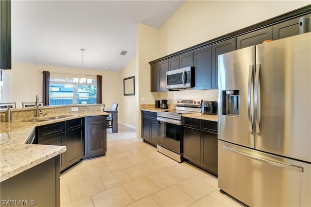 kitchen with light stone countertops, a notable chandelier, pendant lighting, vaulted ceiling, and appliances with stainless steel finishes