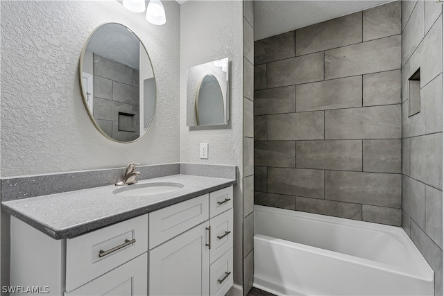 bathroom with tiled shower / bath combo, vanity, and a textured ceiling