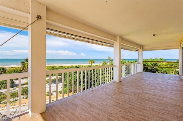 wooden terrace featuring a water view and a view of the beach