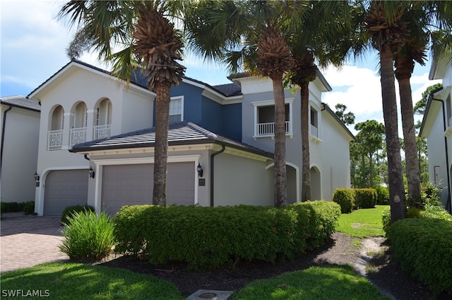 mediterranean / spanish-style home featuring decorative driveway, an attached garage, a balcony, and stucco siding