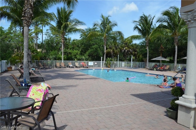 community pool with a patio area and fence