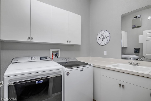 washroom with cabinet space, independent washer and dryer, and a sink