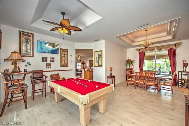 rec room featuring light wood-type flooring, ceiling fan with notable chandelier, a raised ceiling, and pool table