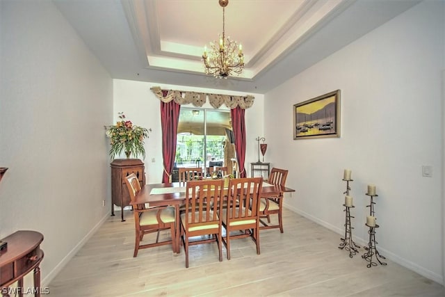 dining room featuring a raised ceiling, a chandelier, and light hardwood / wood-style floors