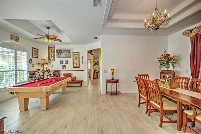 recreation room with a tray ceiling, light hardwood / wood-style floors, ceiling fan with notable chandelier, and pool table