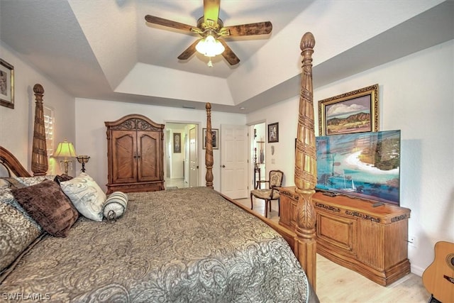 bedroom with ceiling fan, a raised ceiling, and light hardwood / wood-style flooring