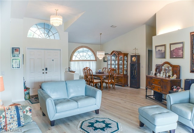 living room with high vaulted ceiling, an inviting chandelier, and hardwood / wood-style flooring