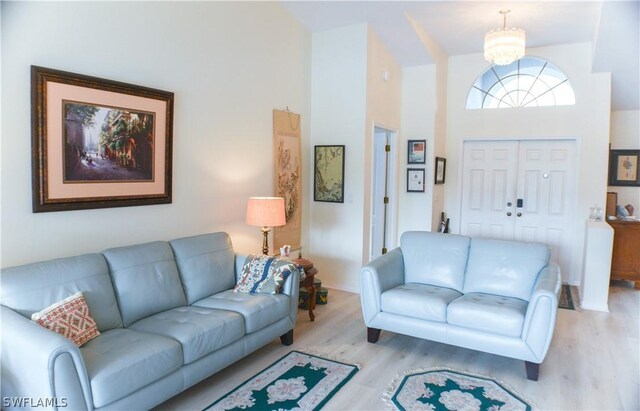 living room with a notable chandelier, hardwood / wood-style floors, and a high ceiling