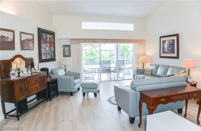 living room featuring high vaulted ceiling and light wood-type flooring