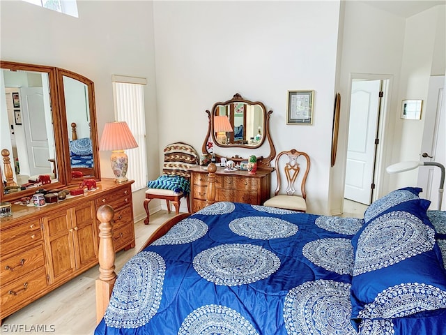 bedroom featuring a towering ceiling and light hardwood / wood-style flooring