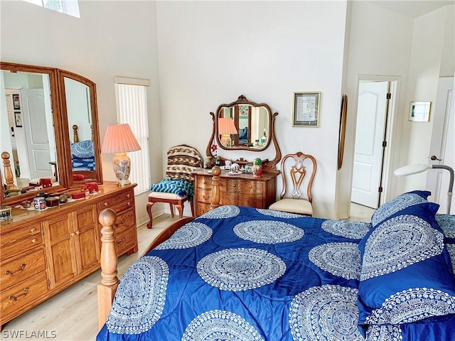 bedroom featuring light wood finished floors and a towering ceiling