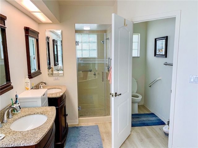 bathroom featuring vanity with extensive cabinet space, an enclosed shower, hardwood / wood-style flooring, and toilet