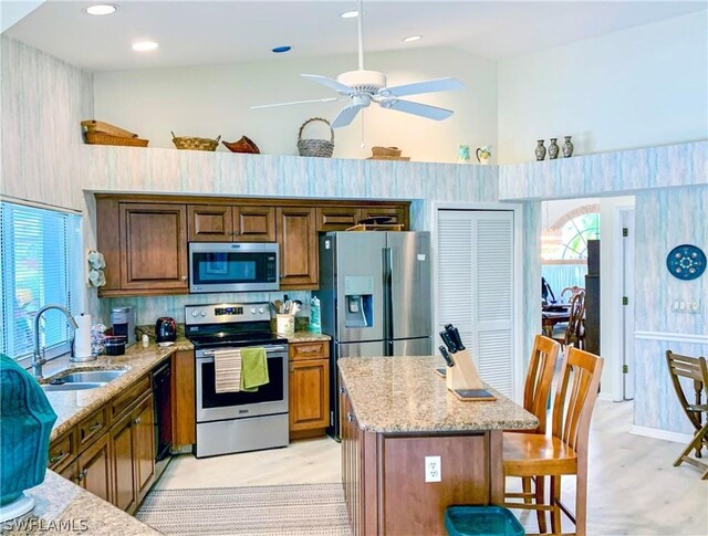 kitchen with a kitchen island, stainless steel appliances, high vaulted ceiling, sink, and ceiling fan