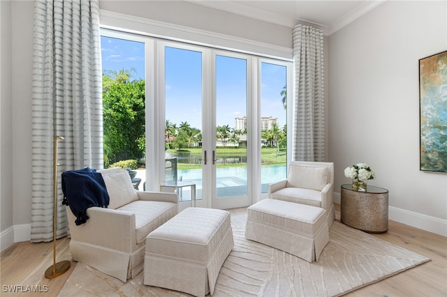 living area with a water view, ornamental molding, plenty of natural light, and light wood-type flooring