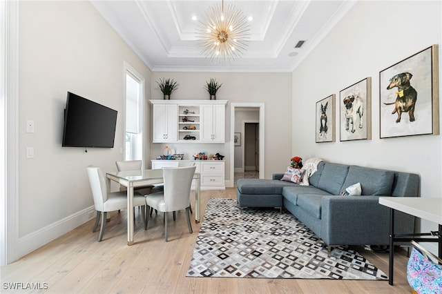 living room featuring light hardwood / wood-style floors, a raised ceiling, an inviting chandelier, and crown molding