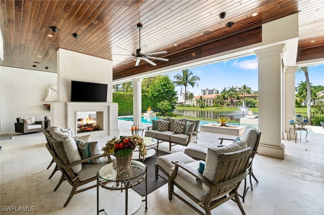 view of patio / terrace featuring ceiling fan and an outdoor living space with a fireplace