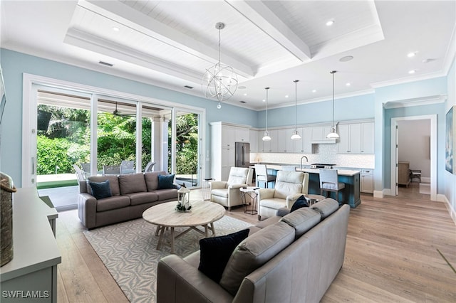 living room with sink, light hardwood / wood-style floors, beamed ceiling, ornamental molding, and an inviting chandelier