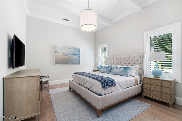 bedroom featuring beam ceiling and light hardwood / wood-style flooring