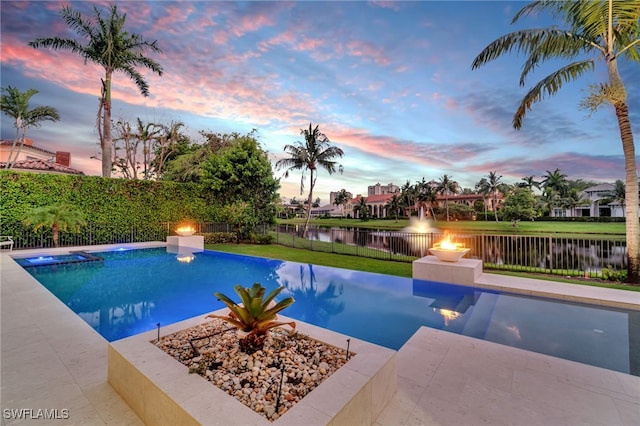 pool at dusk with a patio area, a yard, and a water view