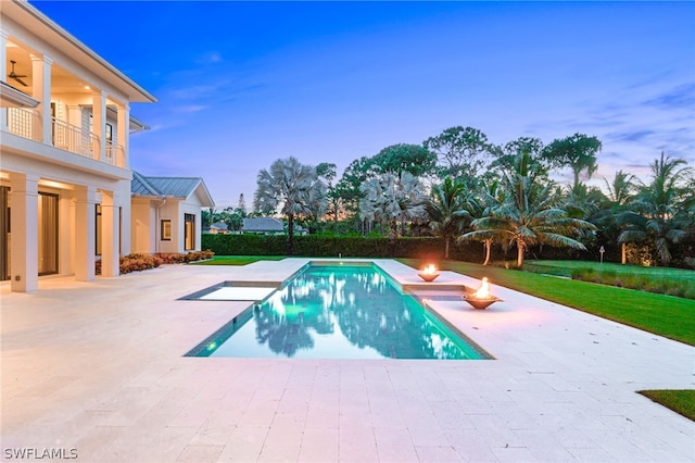 pool at dusk featuring a patio