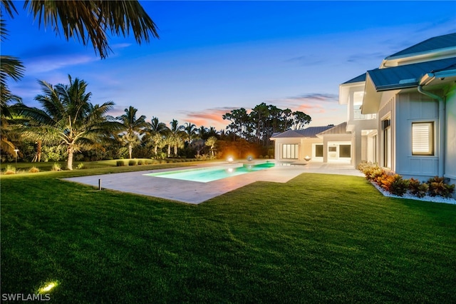 pool at dusk with a yard and a patio