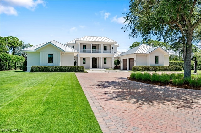 view of front of house featuring a balcony, a front lawn, and a garage