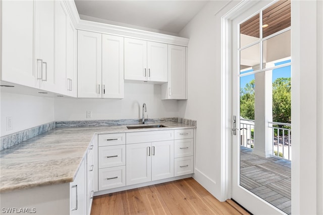 kitchen featuring light stone counters, sink, white cabinets, and light hardwood / wood-style floors