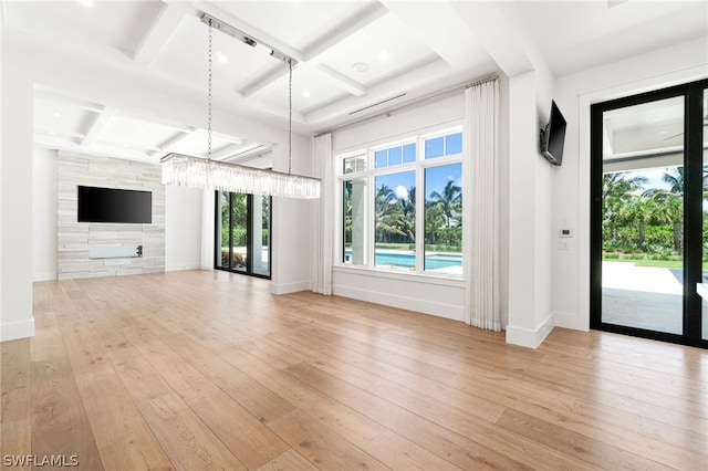 unfurnished living room featuring a chandelier, beam ceiling, light wood-type flooring, and coffered ceiling