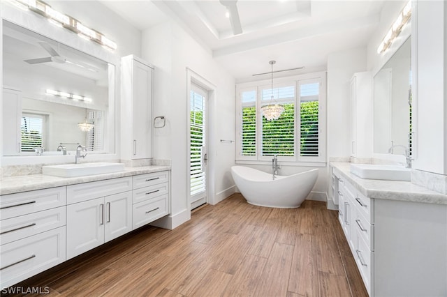 bathroom with hardwood / wood-style flooring, vanity, a bathing tub, and a notable chandelier