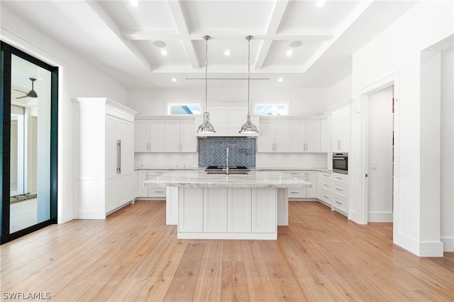 kitchen featuring stainless steel oven, decorative light fixtures, light hardwood / wood-style flooring, a center island with sink, and white cabinetry