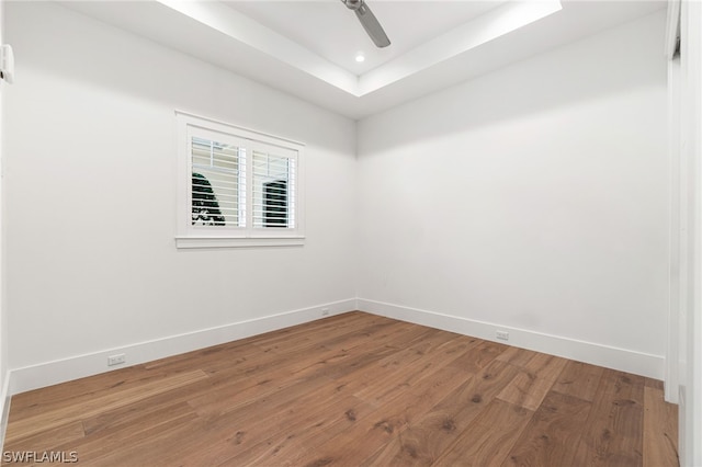 spare room with hardwood / wood-style floors, a raised ceiling, and ceiling fan