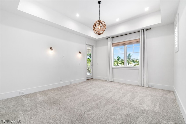 carpeted spare room featuring a tray ceiling