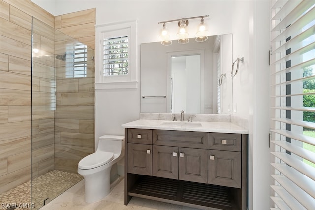 bathroom with a tile shower, vanity, and toilet