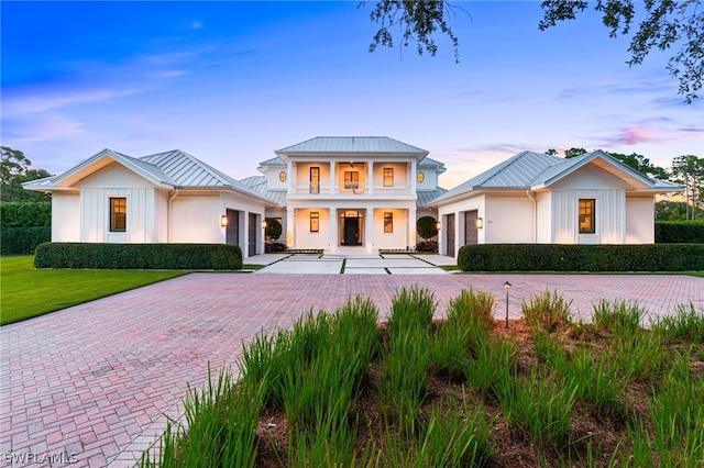171 N St, Naples, FL 34108 - greek revival house featuring a garage, decorative driveway, metal roof, a balcony, and covered porch