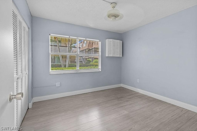 unfurnished bedroom with a textured ceiling, light wood-type flooring, a closet, and ceiling fan