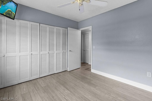 unfurnished bedroom with a textured ceiling, a closet, light hardwood / wood-style flooring, and ceiling fan