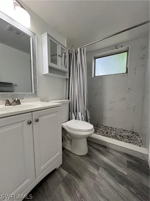 bathroom featuring vanity, toilet, and curtained shower