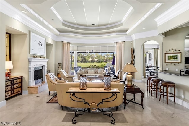 tiled living room featuring crown molding, a fireplace, and a tray ceiling