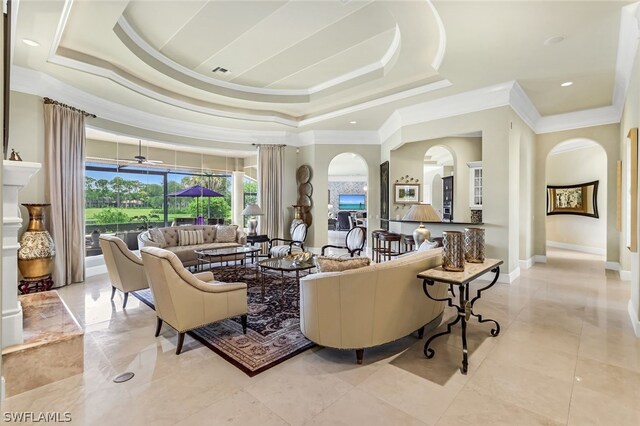 living room featuring a towering ceiling, ornamental molding, and a raised ceiling