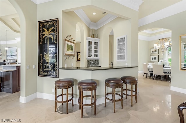 kitchen with pendant lighting, tasteful backsplash, a breakfast bar area, a raised ceiling, and crown molding