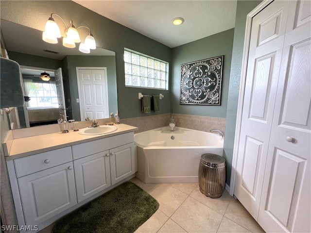 bathroom featuring a wealth of natural light, vanity with extensive cabinet space, tile flooring, and a bath to relax in