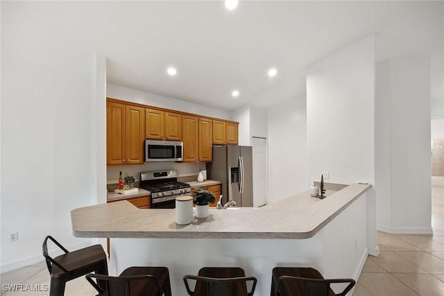 1732 Tarpon Bay Dr S Unit 203, Naples, FL 34119 - kitchen featuring stainless steel appliances, a kitchen bar, light tile patterned floors, light countertops, and recessed lighting