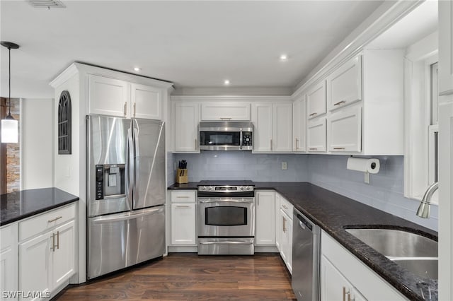 kitchen with tasteful backsplash, stainless steel appliances, hanging light fixtures, dark hardwood / wood-style floors, and white cabinetry