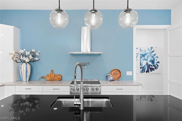 kitchen featuring white cabinets, wall chimney exhaust hood, light stone counters, and hanging light fixtures