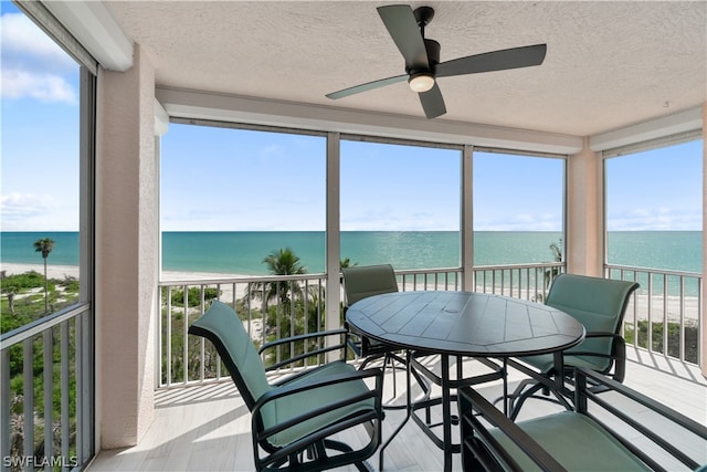 sunroom featuring a water view, a wealth of natural light, and ceiling fan