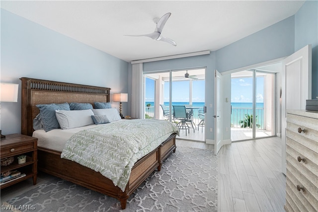 bedroom featuring access to outside, ceiling fan, wood-type flooring, and a water view