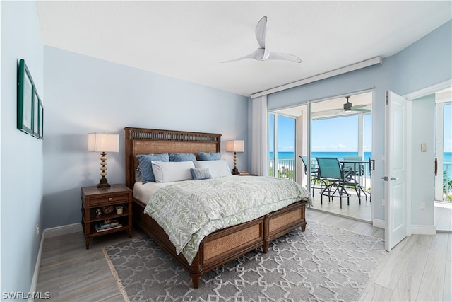 bedroom with access to exterior, a water view, ceiling fan, and hardwood / wood-style flooring