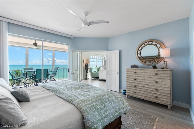 bedroom with ceiling fan, access to outside, hardwood / wood-style flooring, and a water view